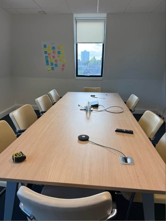 Conference room with a large table, chairs, and a window showing a cityscape.