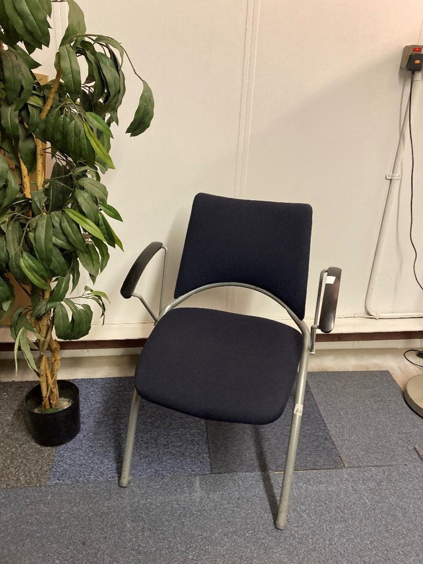 Stick chair with armrests next to a tall green plant