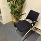 Blue waiting area chair with armpads next to a tall green plant