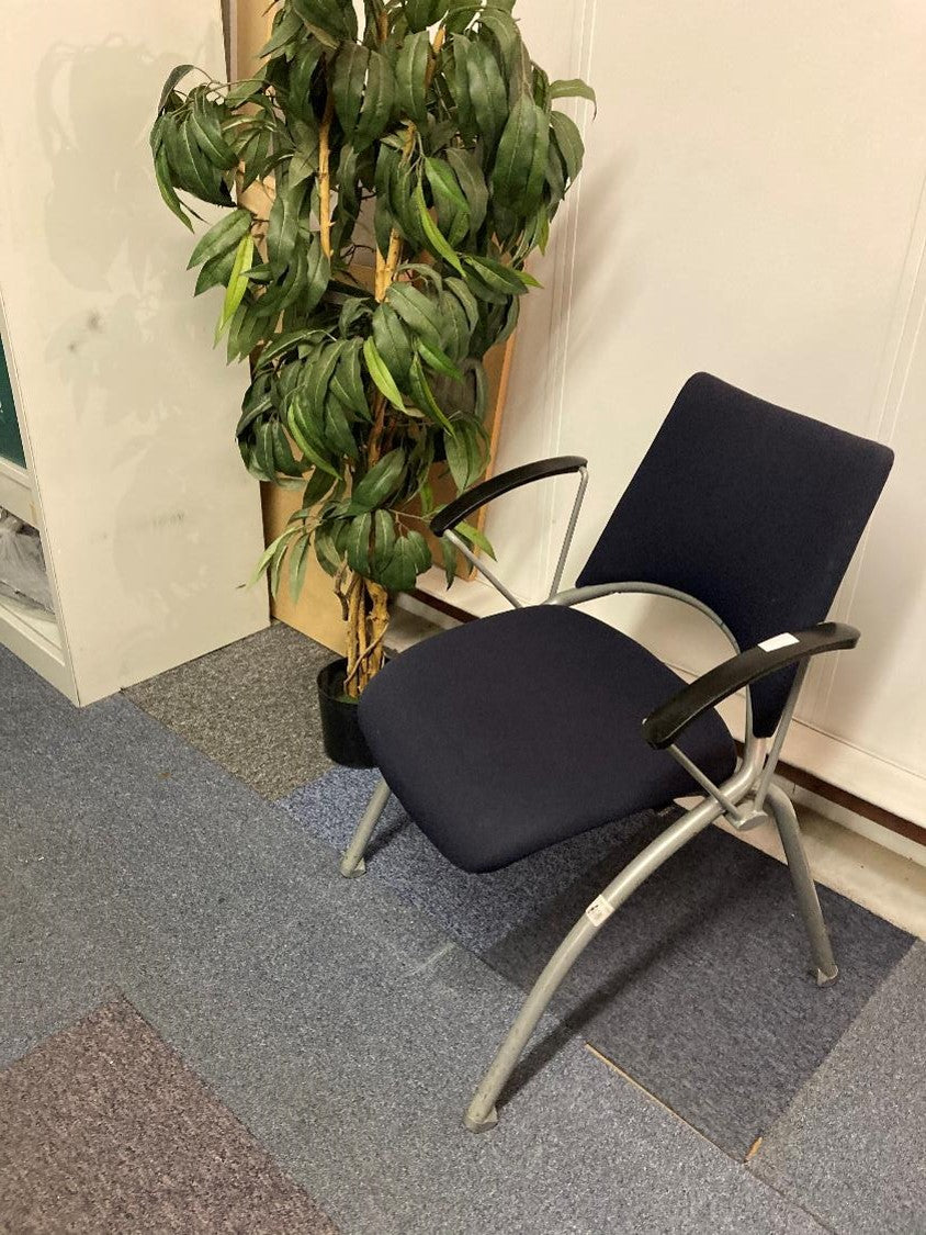 Blue waiting area chair with armpads next to a tall green plant
