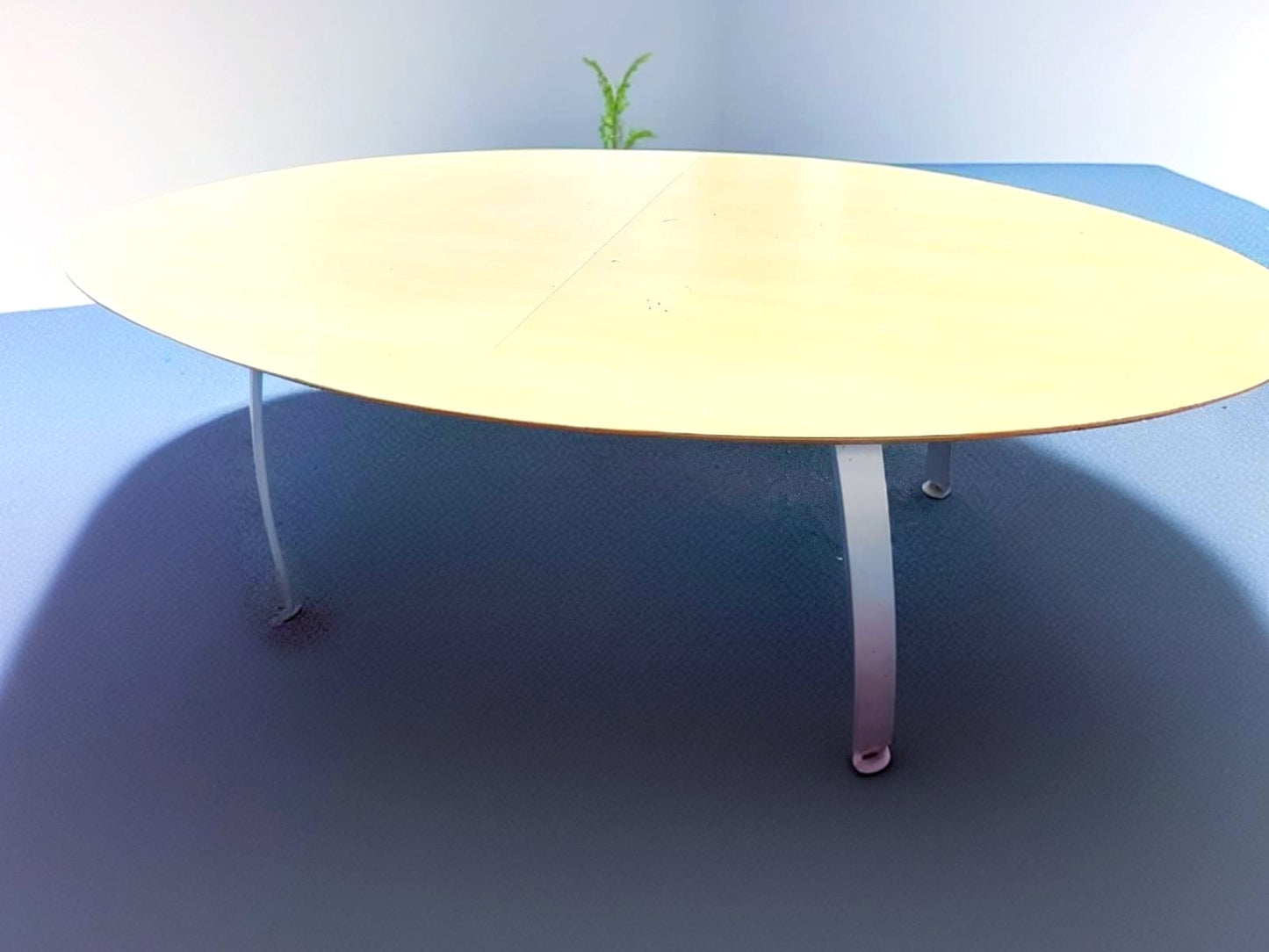 Secondhand maple-coloured boardroom table features a distinctive oval shape supported by four silver legs.