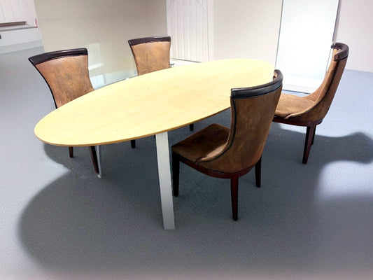 Secondhand maple-coloured boardroom table features a distinctive oval shape supported by four silver legs.
