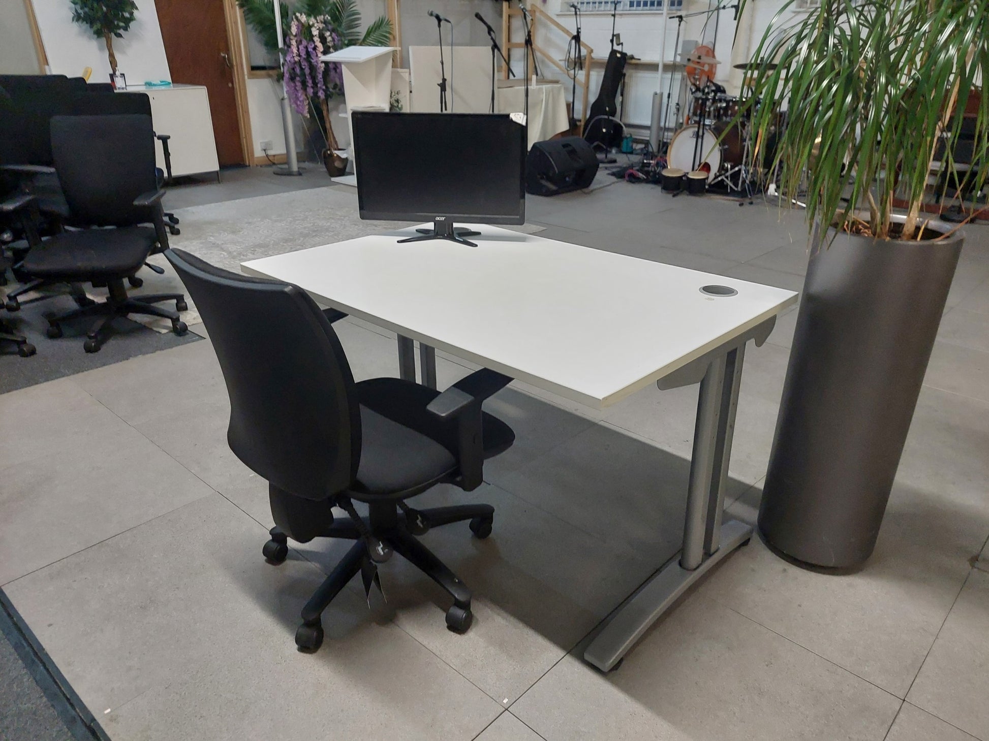 Monitor screen and black swivel chair on White office desk in large room