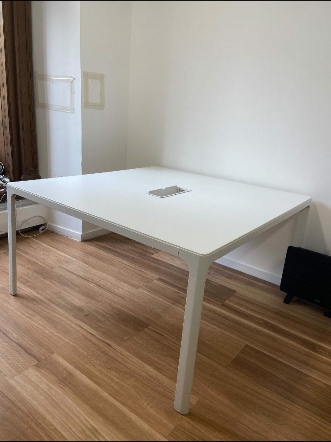 White office table in a room with wooden flooring and a white wall.