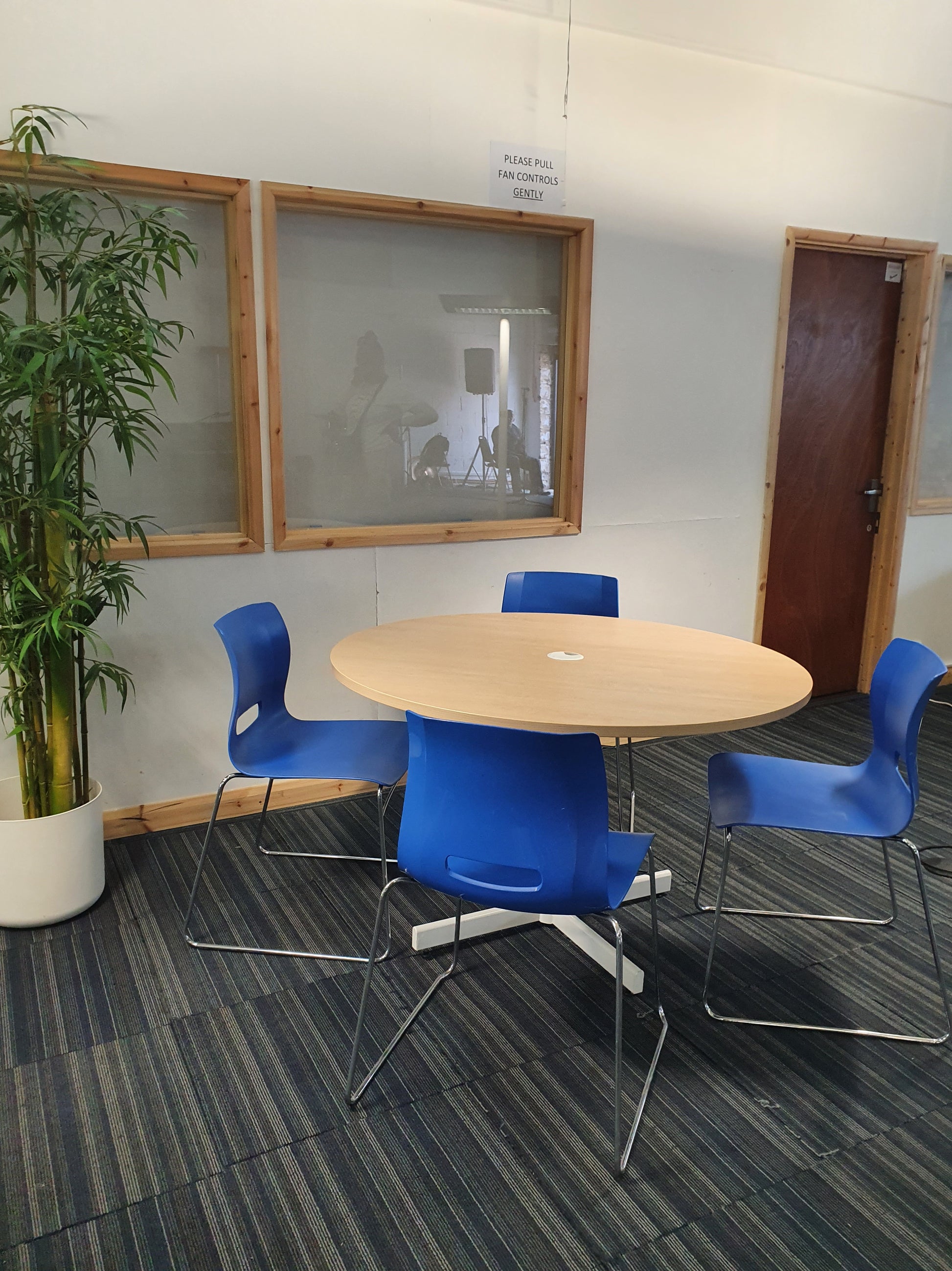 Left, tall green plant, centre, brown round table and four blue senator dining chairs