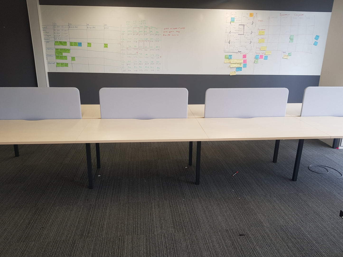 Large Whiteboard hung in an office with an eight seat office table with grey screens