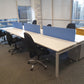 Bank of six office desks in white and six black chairs