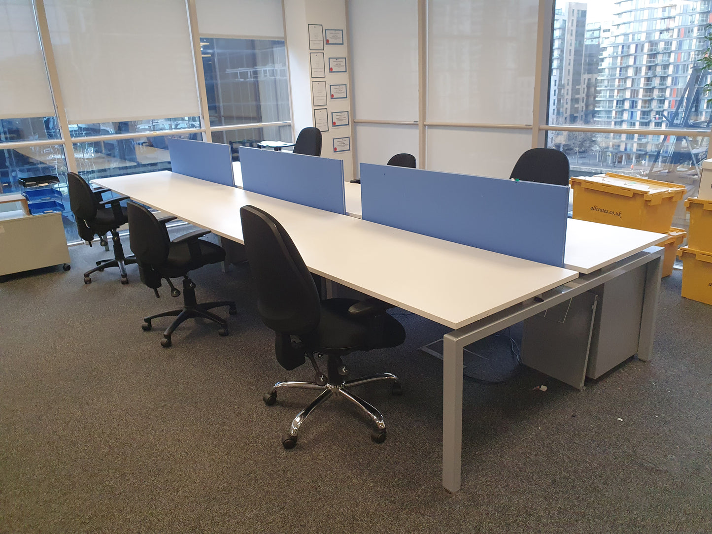 Bank of six office desks in white and six black chairs