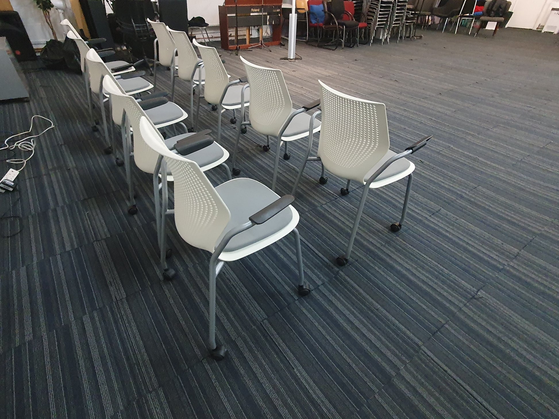 Multiple white chairs on wheels in large hall