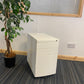 Left, tall green plant, centre, White under desk office drawer