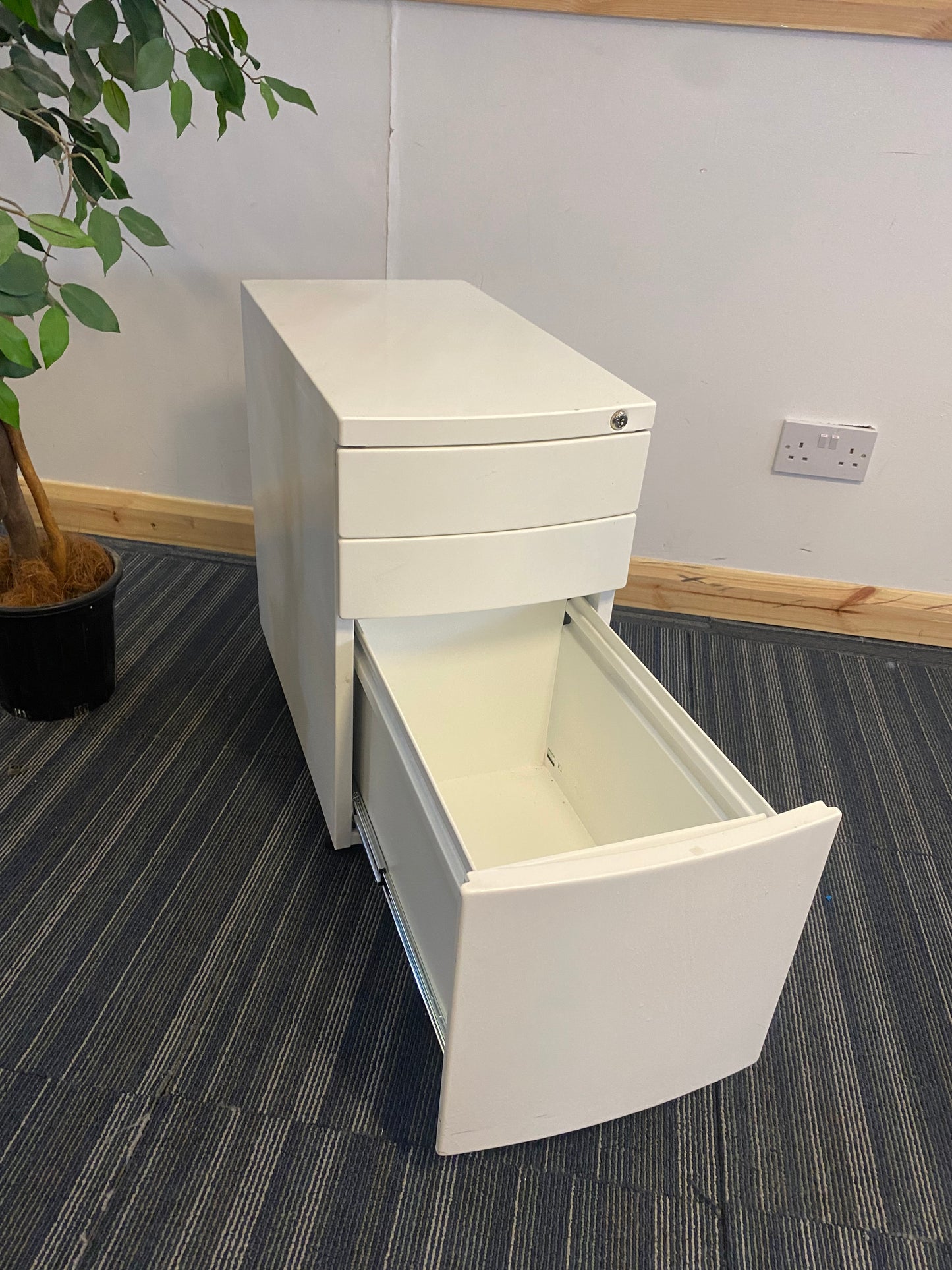 Left, tall green plant, centre, White office drawer with open third, bottom drawer